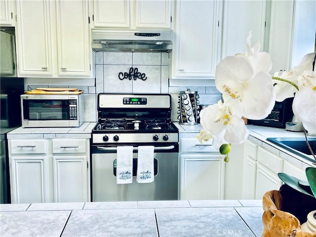 9830 Mesquite Ave, Desert Hot Springs, CA 92240 - kitchen featuring stainless steel appliances, under cabinet range hood, tile counters, and backsplash