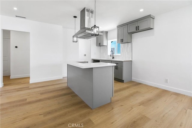 1736 N Mcdivitt Ave, Compton, CA 90221 - kitchen with island exhaust hood, gray cabinets, light countertops, light wood-type flooring, and hanging light fixtures