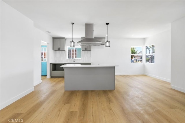 1736 N Mcdivitt Ave, Compton, CA 90221 - kitchen featuring island exhaust hood, gray cabinetry, light countertops, a kitchen island, and light wood-type flooring
