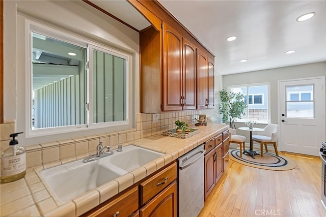 2781 Vuelta Grande Ave, Long Beach, CA 90815 - kitchen featuring dishwasher, tile counters, light wood-style flooring, backsplash, and brown cabinets