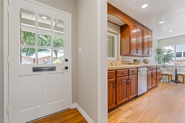 2781 Vuelta Grande Ave, Long Beach, CA 90815 - kitchen with dishwasher, tile countertops, light wood-style floors, backsplash, and brown cabinetry