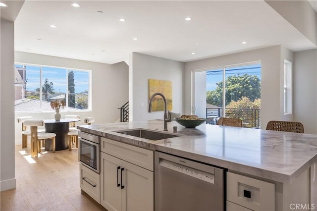2405 Mathews Ave Unit C, Redondo Beach, CA 90278 - kitchen featuring stainless steel dishwasher, an island with sink, light stone counters, light wood-style flooring, and recessed lighting