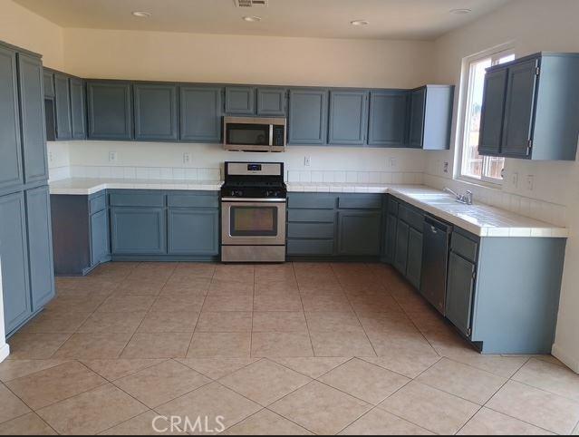 13182 Kootenay, Victorville, CA 92395 - kitchen featuring appliances with stainless steel finishes, light tile patterned floors, tile counters, and recessed lighting
