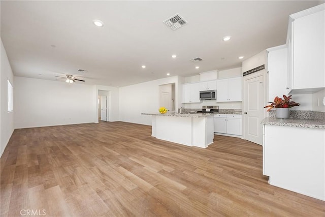 7305 Scrivia Ct, Bakersfield, CA 93311 - kitchen with stainless steel microwave, stove, light wood finished floors, white cabinets, and recessed lighting