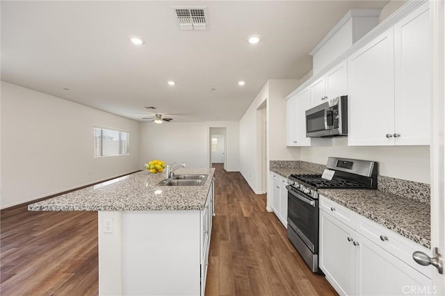 7305 Scrivia Ct, Bakersfield, CA 93311 - kitchen with appliances with stainless steel finishes, ceiling fan, white cabinets, dark wood-type flooring, and a kitchen island with sink