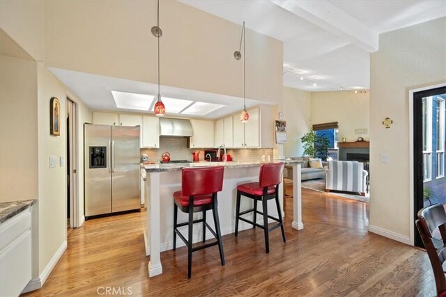 5375 Rosario Ave, Atascadero, CA 93422 - kitchen featuring stainless steel fridge with ice dispenser, decorative backsplash, light wood finished floors, premium range hood, and a breakfast bar area