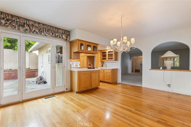 1716 Elm Ave, Manhattan Beach, CA 90266 - kitchen featuring light wood-style flooring, light countertops, arched walkways, a chandelier, and glass insert cabinets