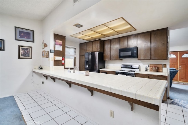 1722 Tiffany Ct, Ontario, CA 91762 - kitchen with white range with gas cooktop, fridge with ice dispenser, black microwave, a kitchen breakfast bar, and dark brown cabinets