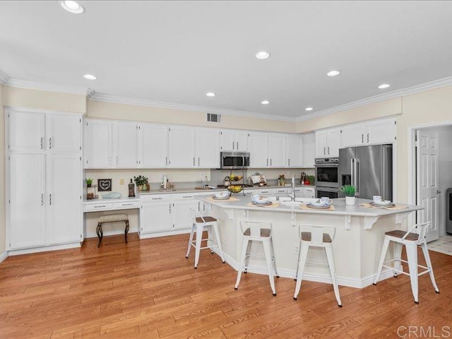 2381 Avenida Helecho, Carlsbad, CA 92009 - kitchen with appliances with stainless steel finishes, white cabinetry, light wood-style floors, a kitchen breakfast bar, and recessed lighting