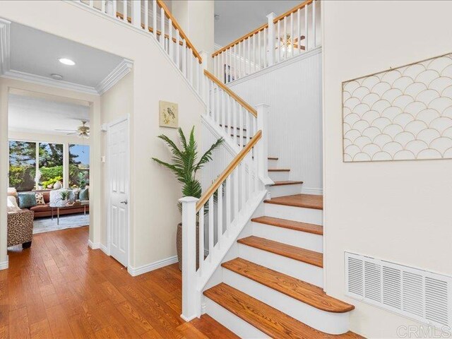 2381 Avenida Helecho, Carlsbad, CA 92009 - stairway featuring ornamental molding, hardwood / wood-style floors, a ceiling fan, and a high ceiling