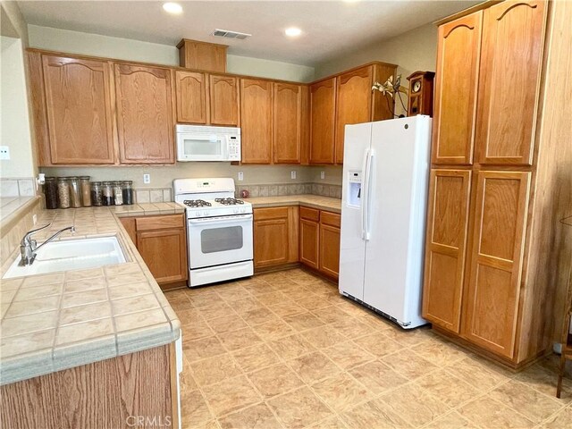 3803 Colma Ct, Merced, CA 95348 - kitchen featuring white appliances, tile counters, recessed lighting, and light floors