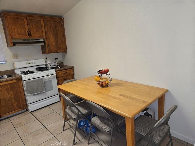 3608 Wagoner Ln, Corona, CA 92879 - kitchen with white range with gas stovetop, under cabinet range hood, and light tile patterned flooring