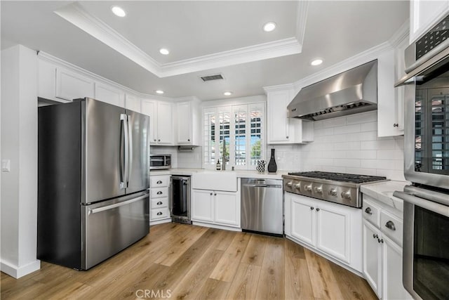 503 Morning Canyon Rd Unit 9, Corona Del Mar, CA 92625 - kitchen with stainless steel appliances, wall chimney range hood, white cabinets, light countertops, and ornamental molding