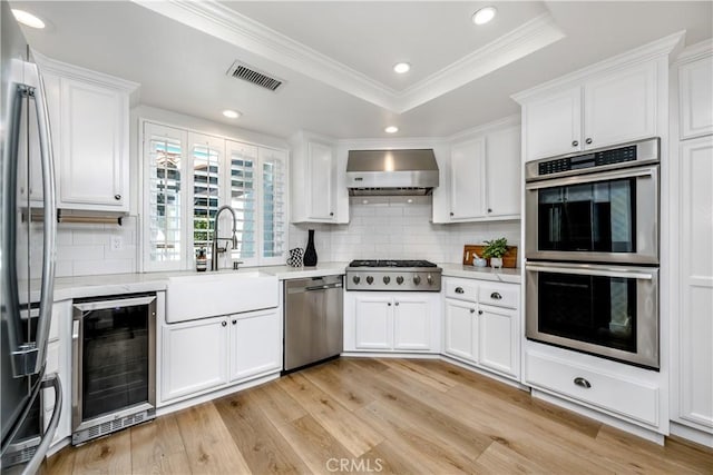503 Morning Canyon Rd Unit 9, Corona Del Mar, CA 92625 - kitchen featuring beverage cooler, stainless steel appliances, wall chimney range hood, light countertops, and white cabinetry