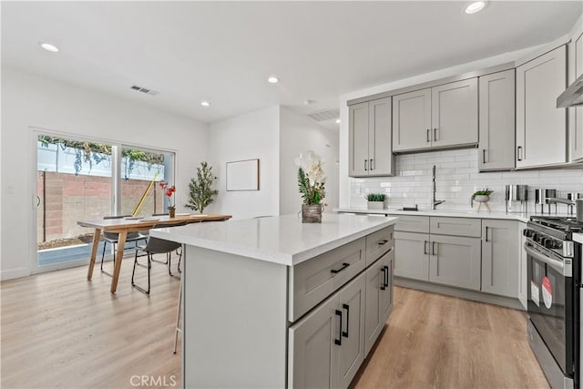13154 Cedar St, Westminster, CA 92683 - kitchen with stainless steel gas range, gray cabinets, light wood-style floors, a kitchen island, and recessed lighting