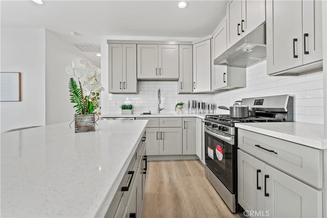 13154 Cedar St, Westminster, CA 92683 - kitchen featuring stainless steel range with gas stovetop, under cabinet range hood, light stone countertops, gray cabinetry, and light wood-type flooring