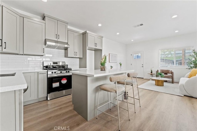 13154 Cedar St, Westminster, CA 92683 - kitchen featuring gas range, under cabinet range hood, light wood-type flooring, decorative backsplash, and light countertops