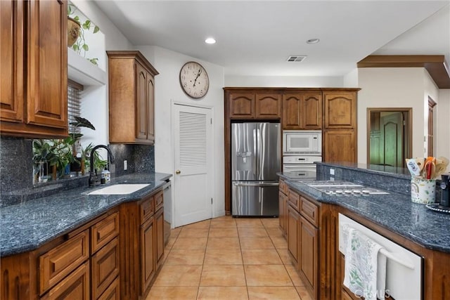 1806 Briercliff Ct, Bakersfield, CA 93311 - kitchen featuring appliances with stainless steel finishes, tasteful backsplash, dark stone counters, brown cabinetry, and recessed lighting