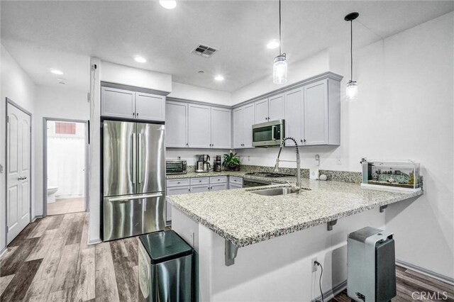 17035 Independence Way, Yorba Linda, CA 92886 - kitchen featuring appliances with stainless steel finishes, a peninsula, a kitchen breakfast bar, wood finished floors, and recessed lighting