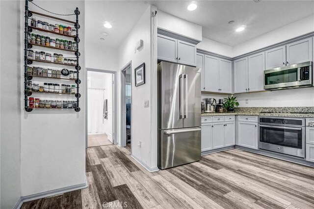 17035 Independence Way, Yorba Linda, CA 92886 - kitchen with appliances with stainless steel finishes, light stone counters, light wood-type flooring, gray cabinetry, and recessed lighting
