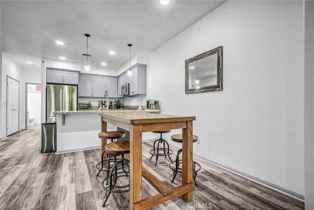 17035 Independence Way, Yorba Linda, CA 92886 - kitchen with stainless steel appliances, gray cabinets, recessed lighting, light wood-type flooring, and a kitchen bar