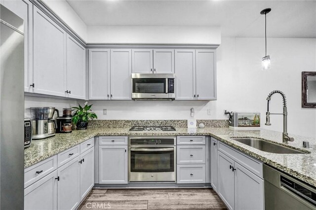 17035 Independence Way, Yorba Linda, CA 92886 - kitchen featuring stainless steel appliances, light wood finished floors, hanging light fixtures, light stone countertops, and a peninsula