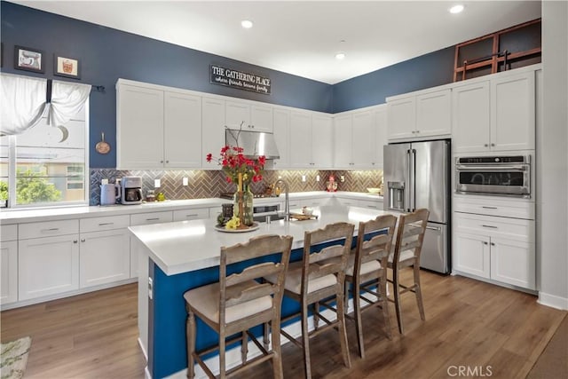 26957 Winding Trail Ct, Valencia, CA 91381 - kitchen with appliances with stainless steel finishes, light countertops, under cabinet range hood, white cabinets, and decorative backsplash