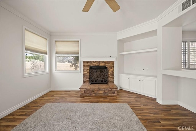 40225 Watford Way, Palmdale, CA 93551 - unfurnished living room with dark wood-style flooring, ornamental molding, a ceiling fan, built in shelves, and a stone fireplace
