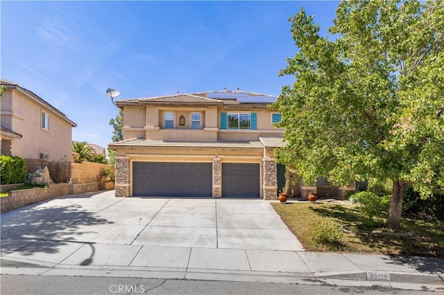 40225 Watford Way, Palmdale, CA 93551 - view of front of house featuring a garage, solar panels, driveway, stucco siding, and stone siding