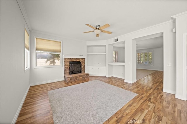 40225 Watford Way, Palmdale, CA 93551 - living room featuring crown molding, built in shelves, a ceiling fan, wood finished floors, and a stone fireplace