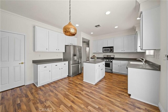40225 Watford Way, Palmdale, CA 93551 - kitchen with stainless steel appliances, dark countertops, crown molding, a kitchen island, and recessed lighting