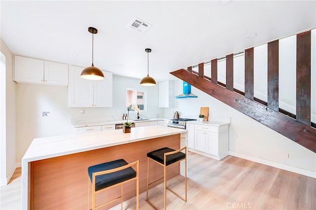 1478 N Park Ave, Pomona, CA 91768 - kitchen featuring white cabinetry, light countertops, light wood-type flooring, a kitchen bar, and hanging light fixtures