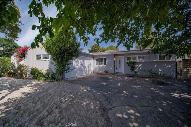 7848 Chastain Ave, Reseda, CA 91335 - view of front facade with asphalt driveway, an attached garage, and board and batten siding