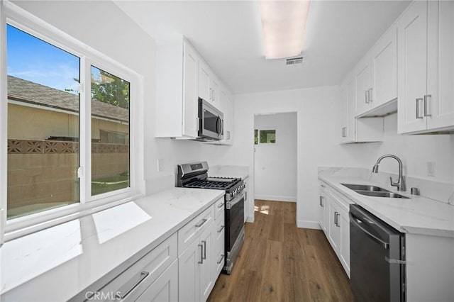 7848 Chastain Ave, Reseda, CA 91335 - kitchen featuring appliances with stainless steel finishes, dark wood-style floors, white cabinets, and light stone counters