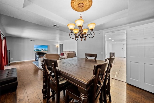 42903 Normandy Ln, Lancaster, CA 93536 - dining room featuring wood-type flooring, a chandelier, and a raised ceiling