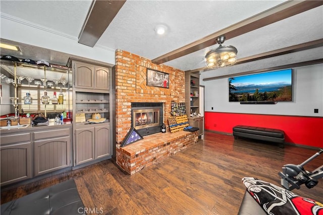 42903 Normandy Ln, Lancaster, CA 93536 - living room featuring beamed ceiling, dark wood-style flooring, a fireplace, a textured ceiling, and built in shelves