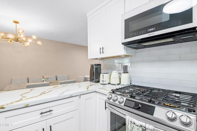 20224 Cohasset St Unit 12, Winnetka, CA 91306 - kitchen featuring stainless steel appliances, decorative backsplash, white cabinetry, a chandelier, and light stone countertops