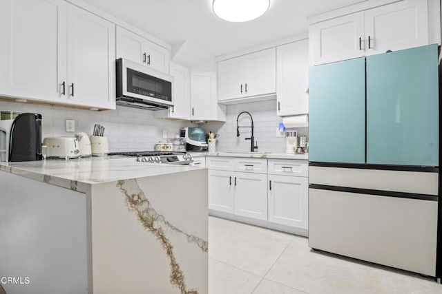 20224 Cohasset St Unit 12, Winnetka, CA 91306 - kitchen with white appliances, white cabinets, decorative backsplash, light stone counters, and light tile patterned floors