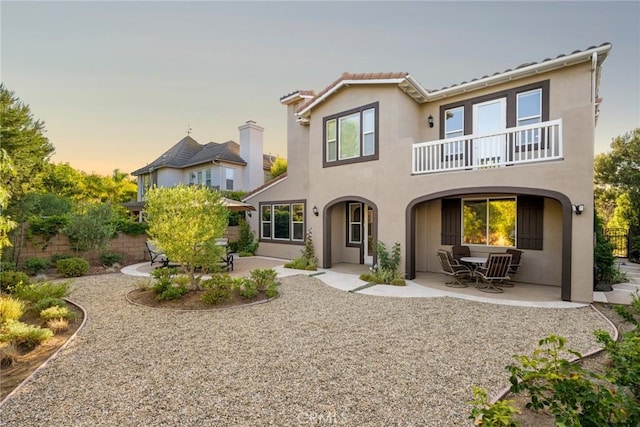 2 Tarascon, Newport Coast, CA 92657 - back of house at dusk featuring a patio, a balcony, and stucco siding