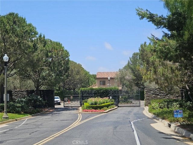 2 Tarascon, Newport Coast, CA 92657 - view of asphalt road featuring a gate, curbs, and street lights