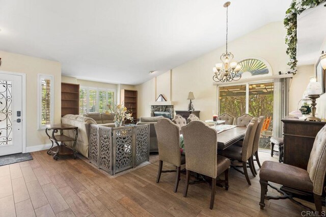 16110 Oak Springs Dr, Ramona, CA 92065 - dining space featuring a chandelier, wood finished floors, vaulted ceiling, and a fireplace