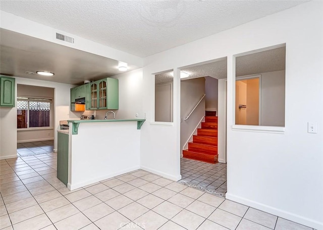 4785 Larwin Ave, Cypress, CA 90630 - kitchen with green cabinets, a textured ceiling, light tile patterned floors, a peninsula, and glass insert cabinets