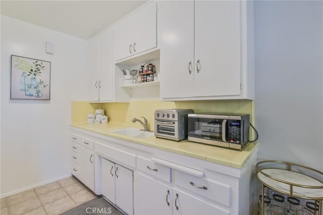 1030 E 2nd St Unit 7, Long Beach, CA 90802 - kitchen with stainless steel microwave, tile counters, white cabinetry, and open shelves