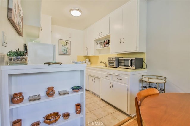 1030 E 2nd St Unit 7, Long Beach, CA 90802 - kitchen with open shelves, stainless steel microwave, light countertops, and white cabinetry