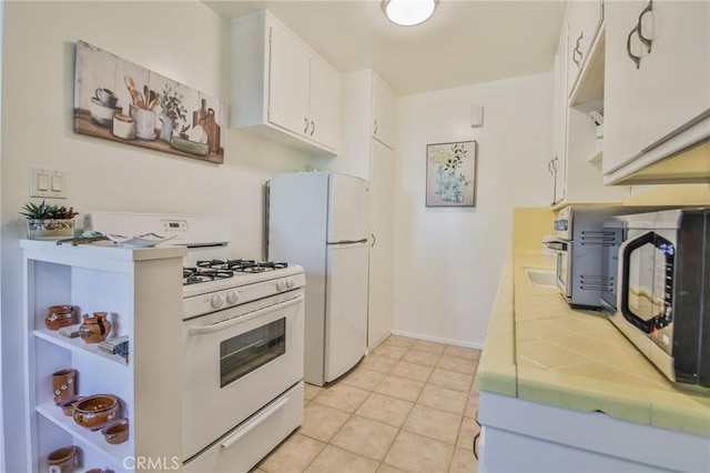 1030 E 2nd St Unit 7, Long Beach, CA 90802 - kitchen featuring white appliances, tile counters, white cabinets, light tile patterned floors, and open shelves