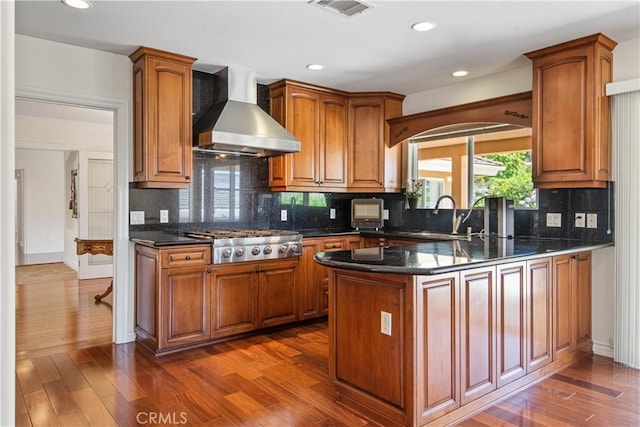 6966 Crest Rd, Rancho Palos Verdes, CA 90275 - kitchen with wall chimney exhaust hood, stainless steel gas stovetop, a peninsula, dark wood-type flooring, and decorative backsplash