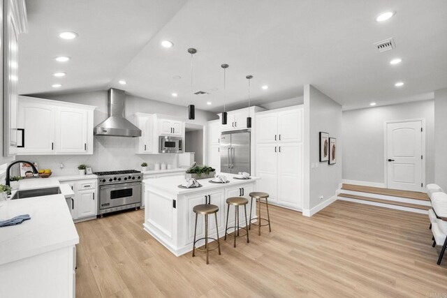 6082 Highland Ave, Yorba Linda, CA 92886 - kitchen with built in appliances, wall chimney exhaust hood, a kitchen breakfast bar, a center island, and light wood-style floors