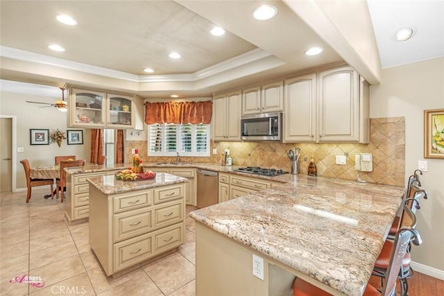 3208 Bridlewood Ct, Bakersfield, CA 93311 - kitchen featuring a peninsula, appliances with stainless steel finishes, light stone counters, crown molding, and a kitchen bar