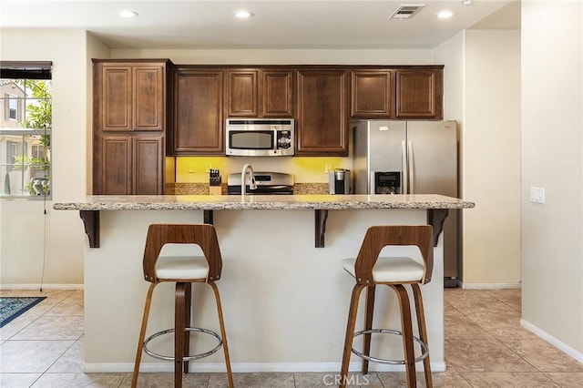 31186 Lavender Ct Unit 164, Temecula, CA 92592 - kitchen with stainless steel appliances, a breakfast bar area, light stone countertops, recessed lighting, and light tile patterned flooring
