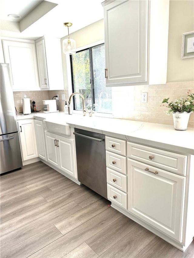 3931 Cottonwood Grove Trl, Calabasas, CA 91301 - kitchen with appliances with stainless steel finishes, light countertops, white cabinets, tasteful backsplash, and light wood-style flooring